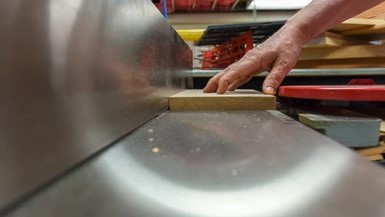 craftsman using jointer machine to straighten board edge