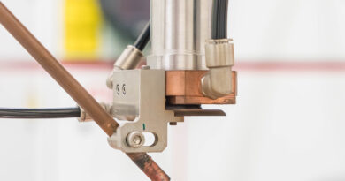 CNC laser cutting head precisely cutting metal sheet in an industrial manufacturing setup.