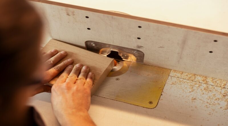 woodworker using a wood shaper machine to route the edge of a wooden board