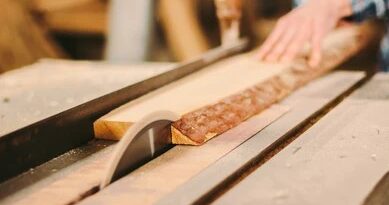 worker cutting a hardwood board on a table saw with a rip fence