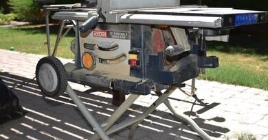 A ryobi 10-inch portable table saw with a folding wheeled stand set up on an outdoor patio