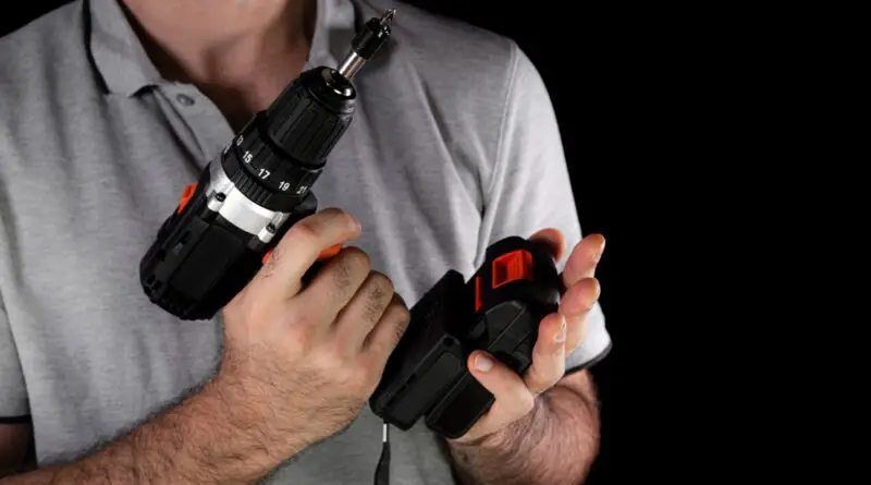 man holding black cordless drill battery preparing to insert into drill driver